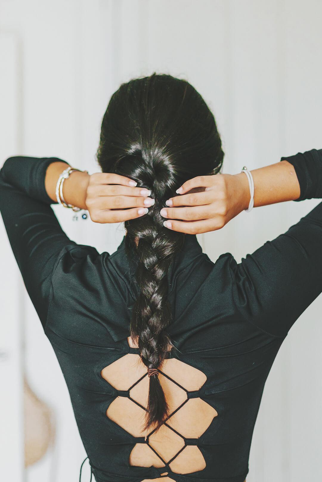A photo of a model's back braiding her own hair Desktop