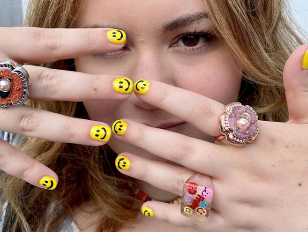 Close-up of Elizabeth Denton showing off her smiley face nail art and cute rings Desktop