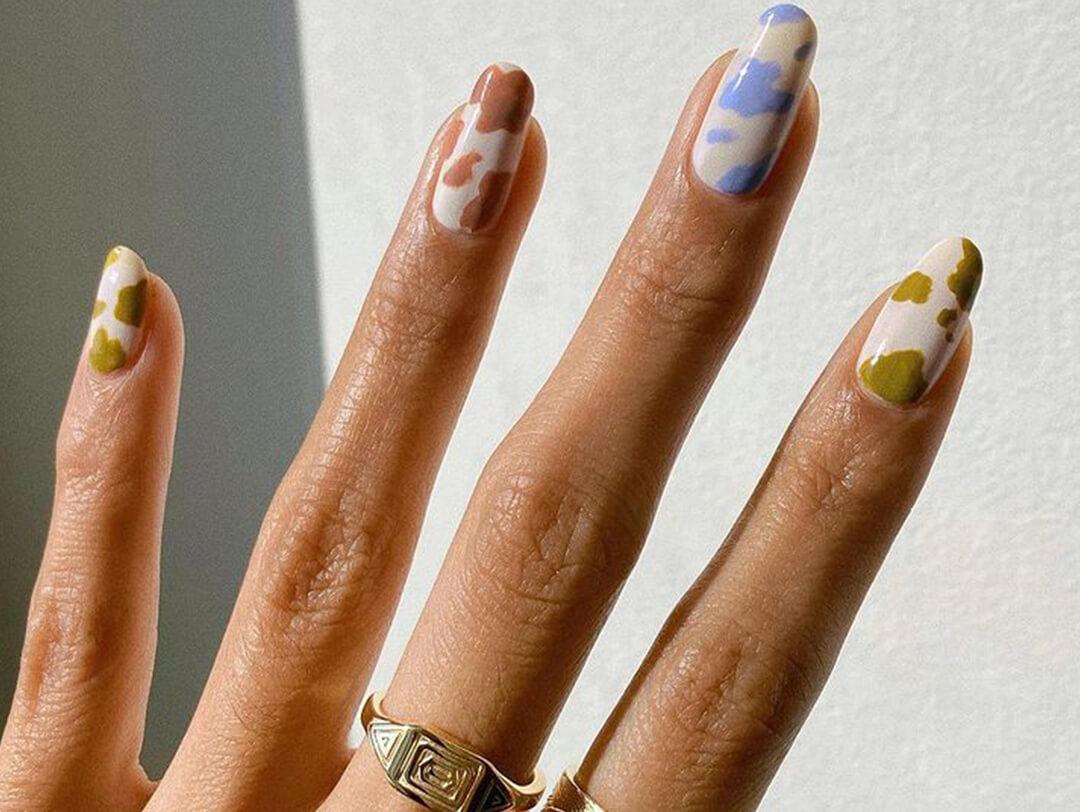 A closeup photo of a model's hand with pastel color cow print nail art Desktop