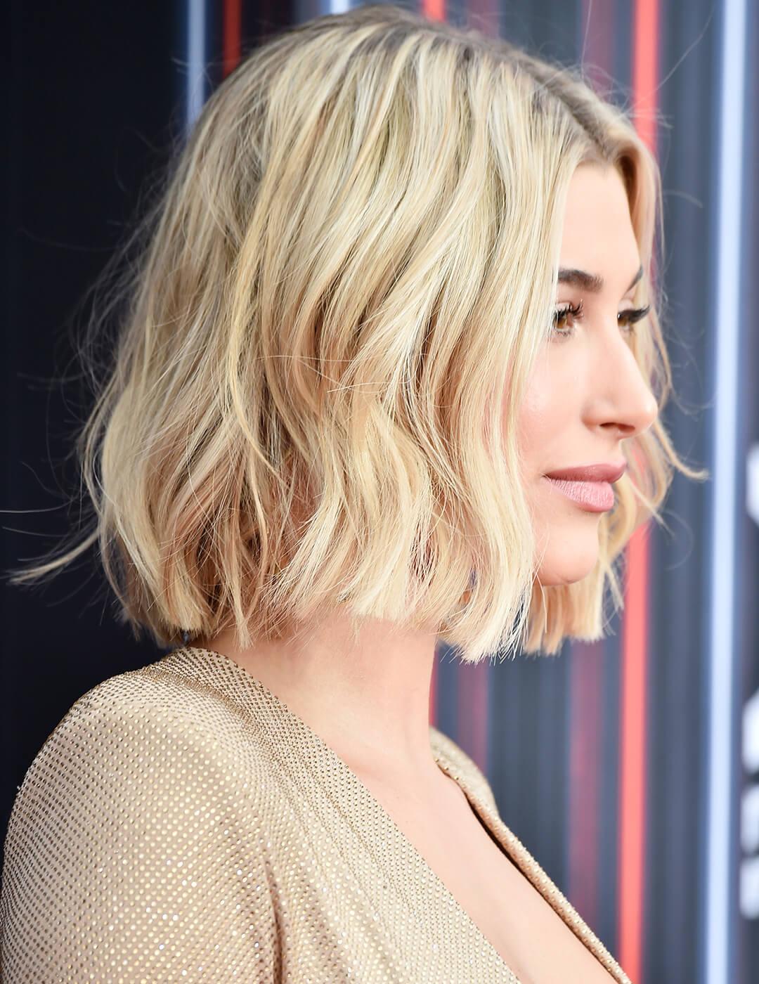 A photo of Hailey Baldwin in sideways characterized by her messy, long bob blonde hair dressed in a stunning beige gown on an abstract background Mobile