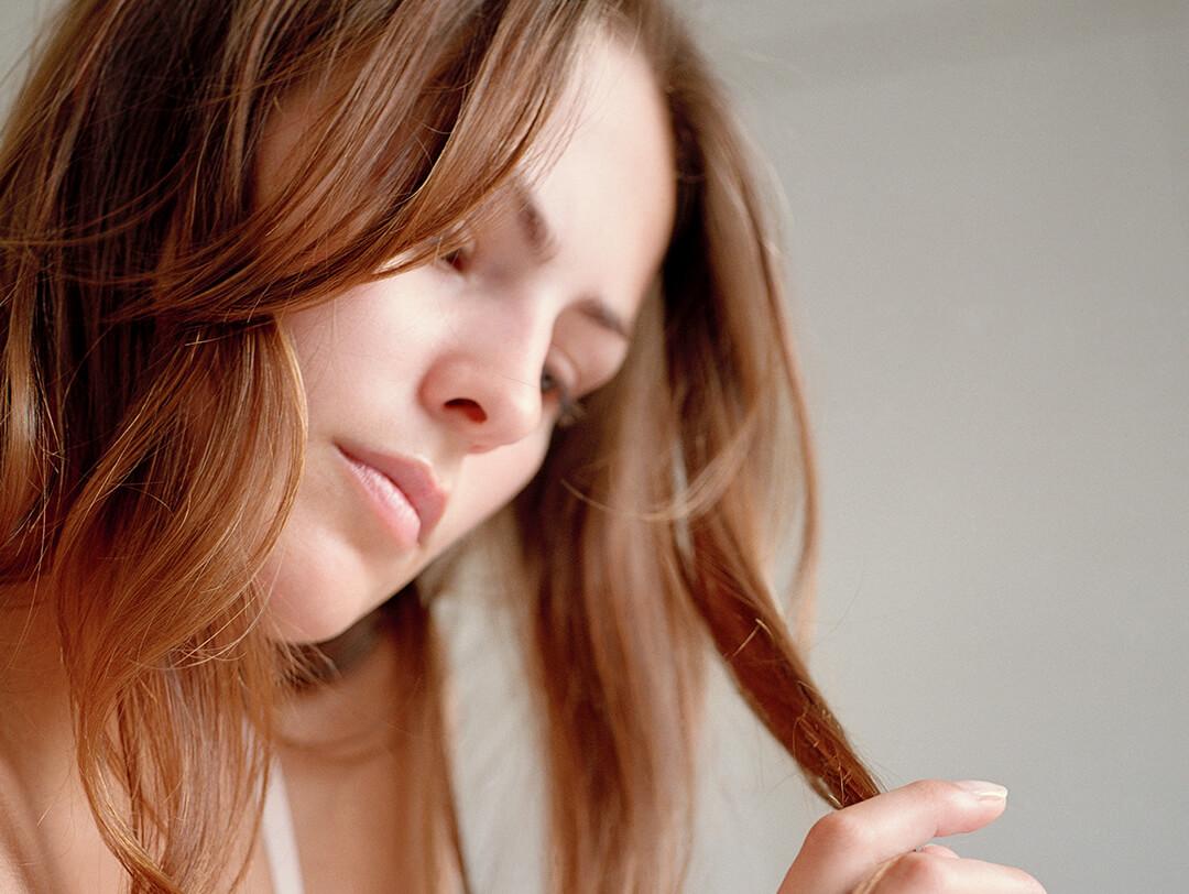 A closeup photo of a model looking at her hair Desktop