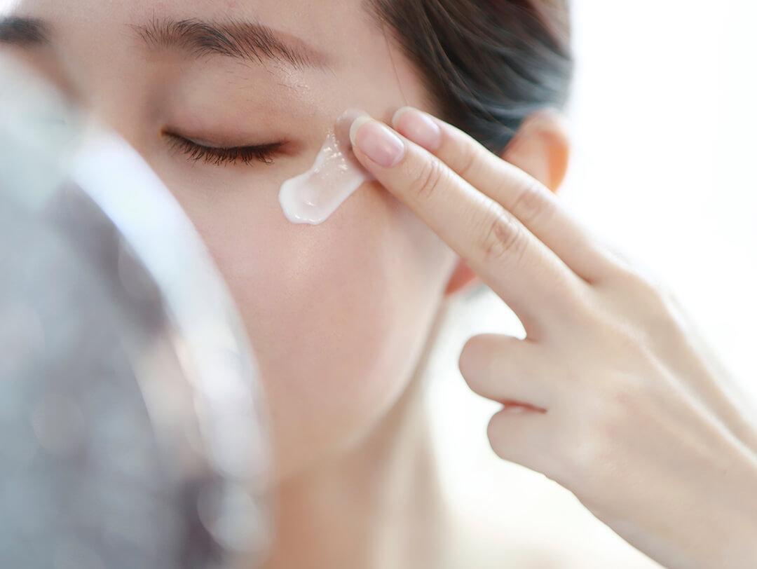 Image of a woman partly covered by her mirror putting on eye cream Desktop