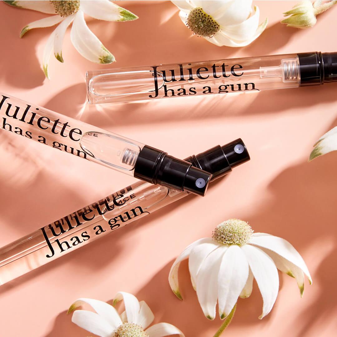 Three tubes of JULIETTE HAS A GUN Lady Vengeance perfume and white flowers on peach background Desktop