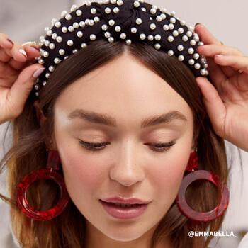 Emma Isabella Holley wearing pearl-studded headband and red statement earrings Mobile