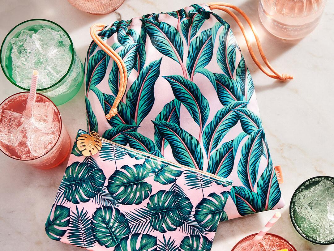August 2022 IPSY Glam Bag and Glam Bag Plus bags together with glasses of green and pink drinks on marble table top Desktop