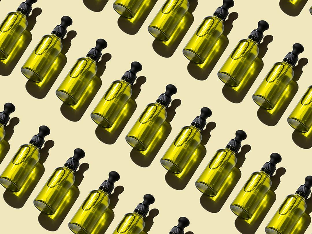 An overhead image of green bottles arranged in a repeating pattern, each containing natural essential oils, against a green backdrop Desktop