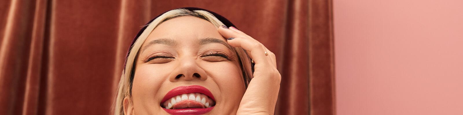 A closeup image of a model with a black headband on touching her forehead while sticking her tongue out Desktop