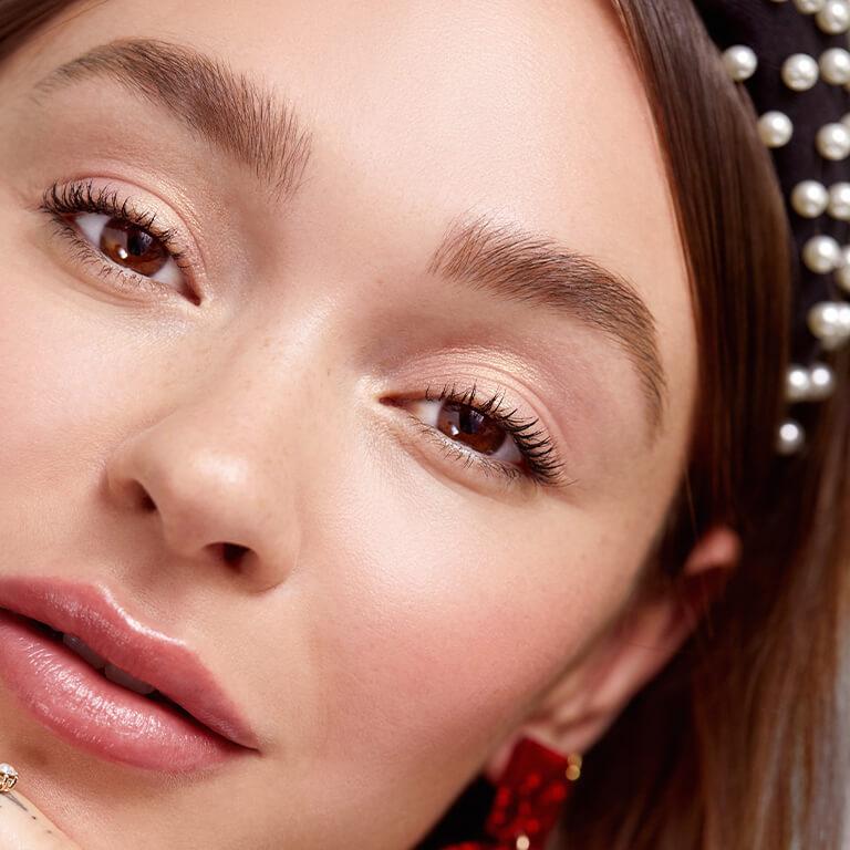 A closeup image of a model with a black headband on touching her forehead while sticking her tongue out Mobile