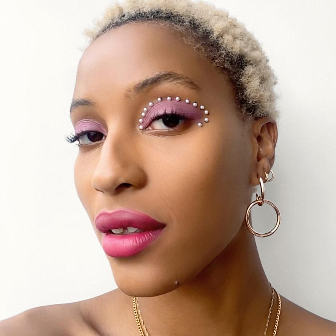 Close-up image of a model rocking a muted pink eyeshadow look embellished with pearls paired with bright berry lipstick Desktop