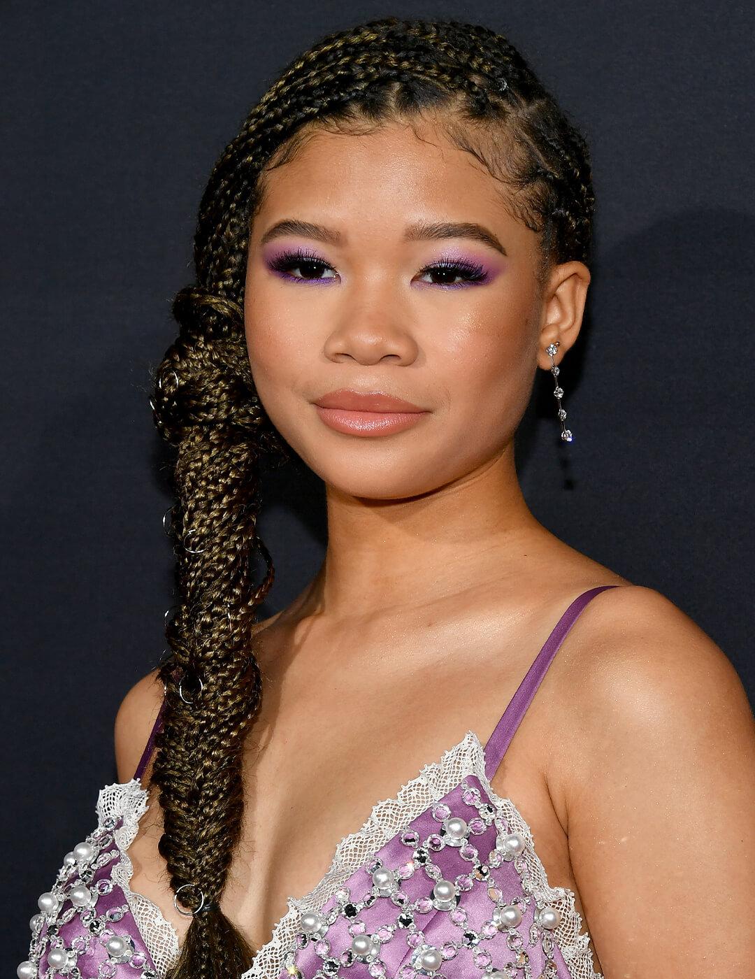 Storm Reid rocking a purple and silver dress and side-swept braided fishtail hairstyle Mobile