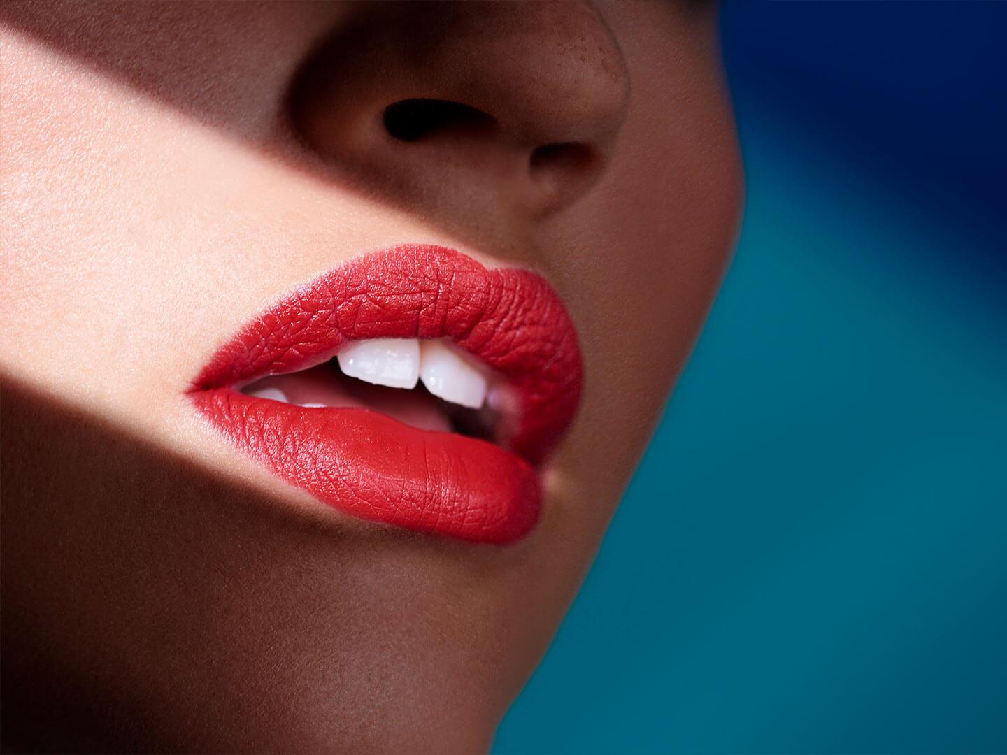 A close-up image of a woman's lips, painted in vibrant red lipstick, illuminated by a beam of sunlight Desktop