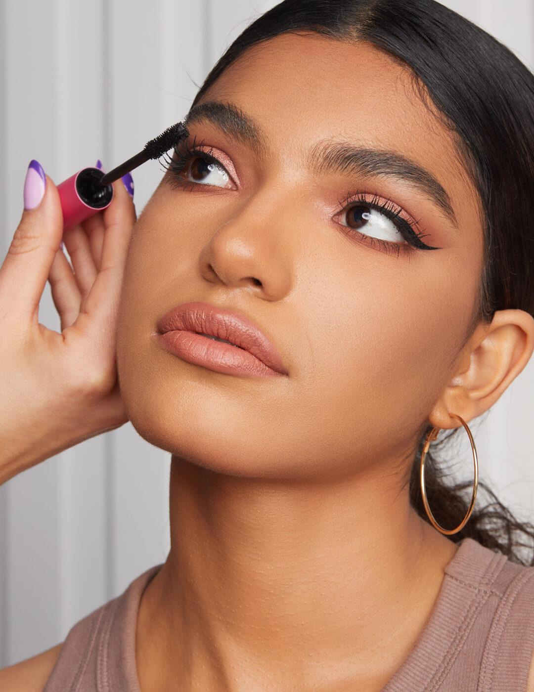 Makeup artist's hand applying mascara on a model's lashes Mobile