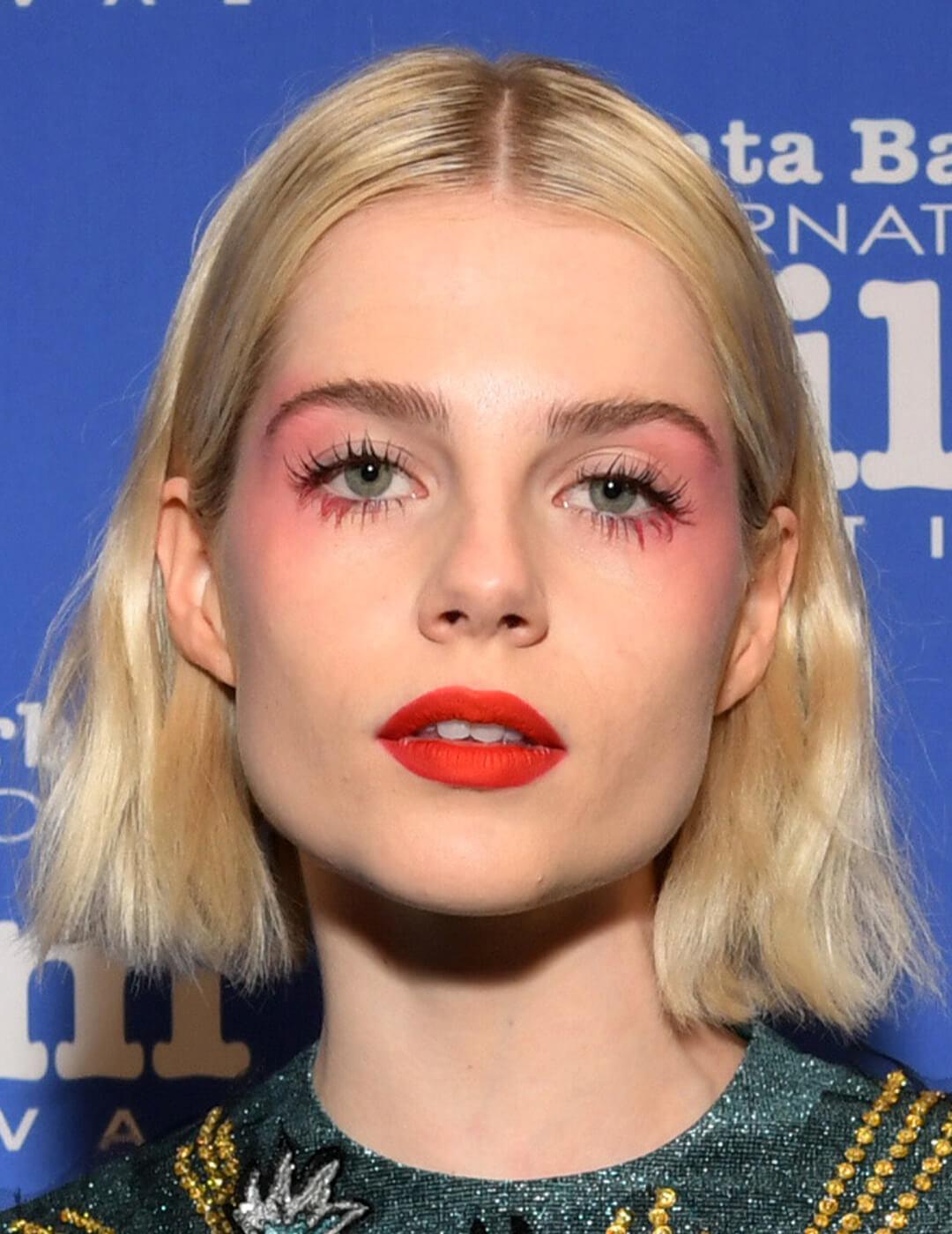 Lucy Boynton rocking a draped blush makeup look paired with bright coral lips Mobile
