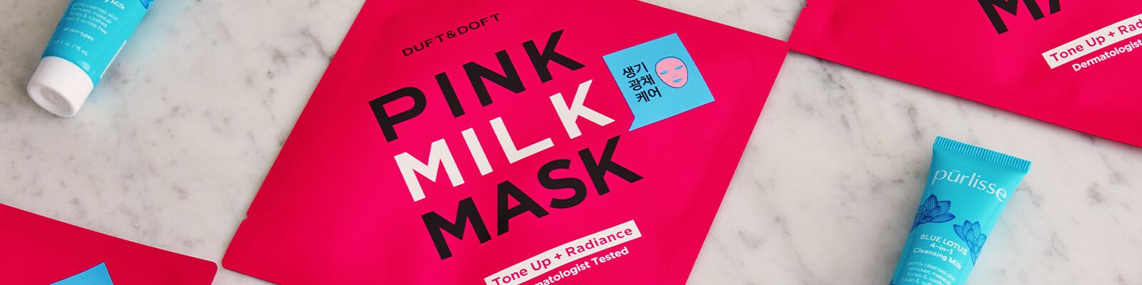 An image of DUFT & DOFT Pink Milk Masks and PURLISSE Blue Lotus 4-in-1 Cleansing Milk neatly arranged Desktop