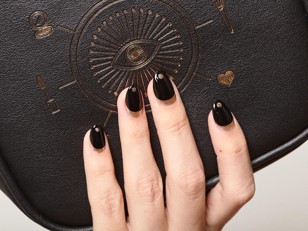 Close-up of a model's hand with black and gold nail art mani holding the IPSY October 2020 Glam Bag Ultimate bag Desktop