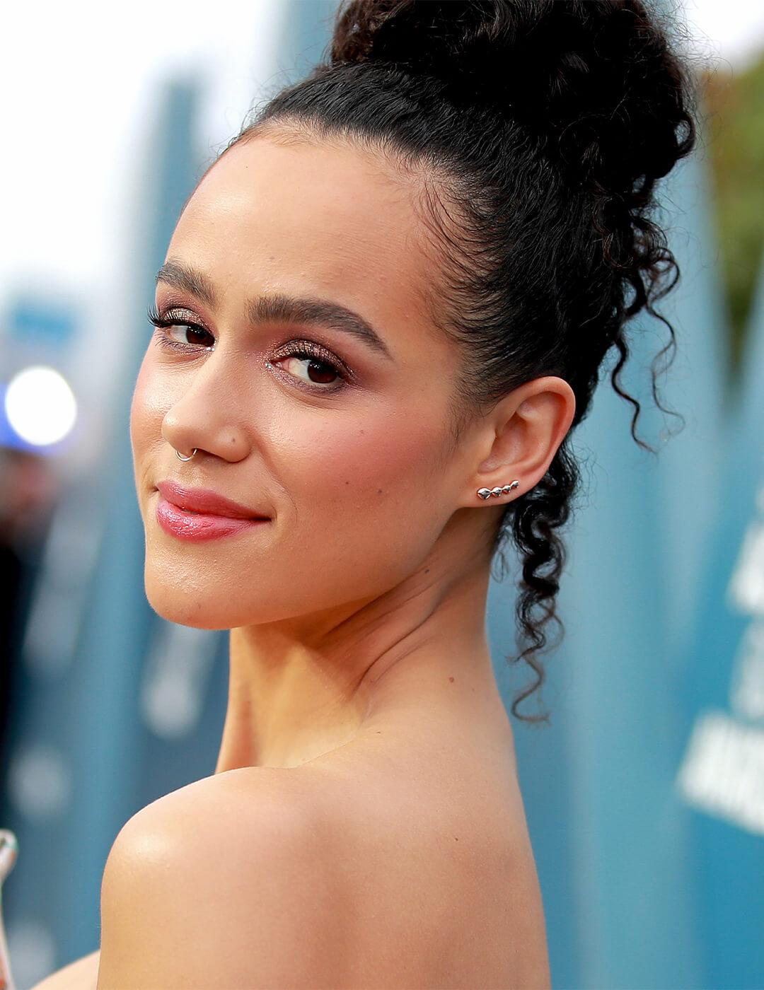 Nathalie Emmanuel wearing a loose top knot hairstyle smiling Desktop