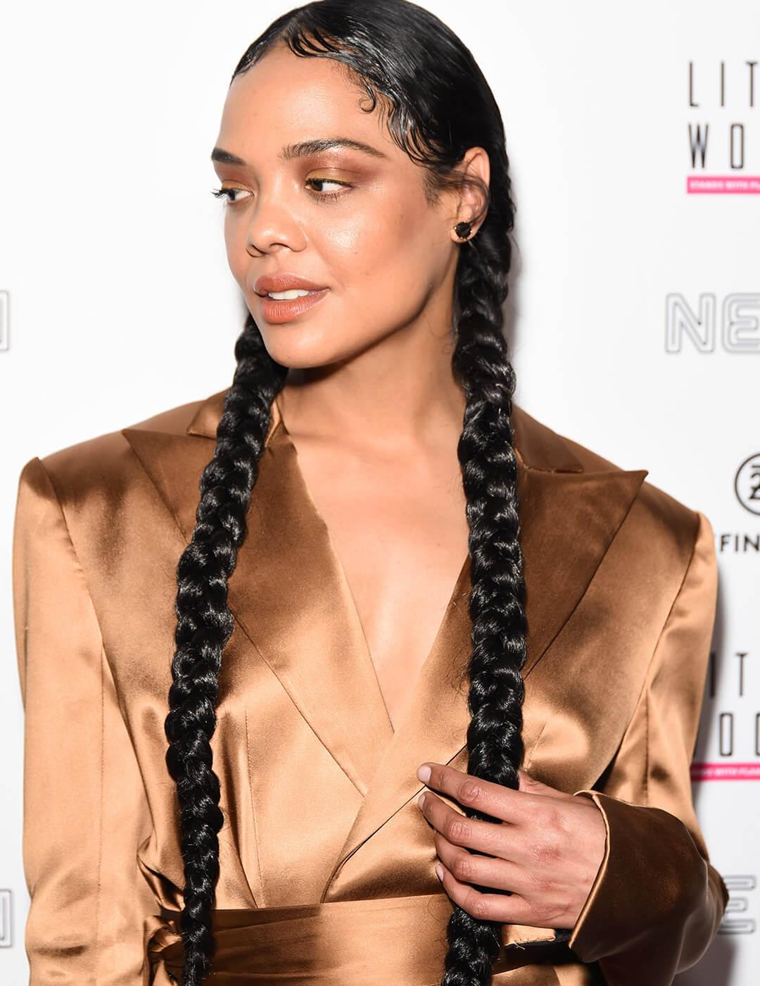 Tessa Thompson looking fierce in a braided pigtails hairstyle, bronze makeup look, and bronze suit Desktop